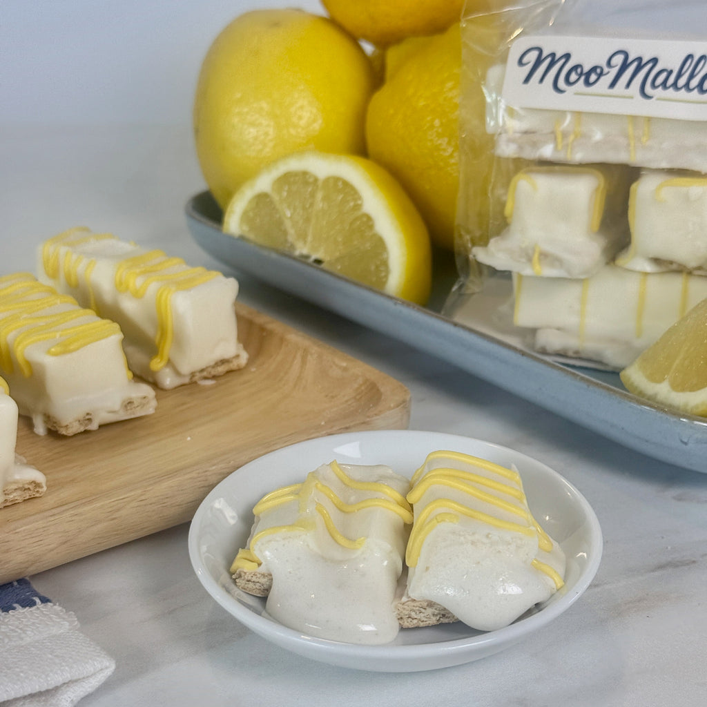 Lemon-flavored treats on a plate with lemons and a package labeled 'Moo Mallow' in the background.